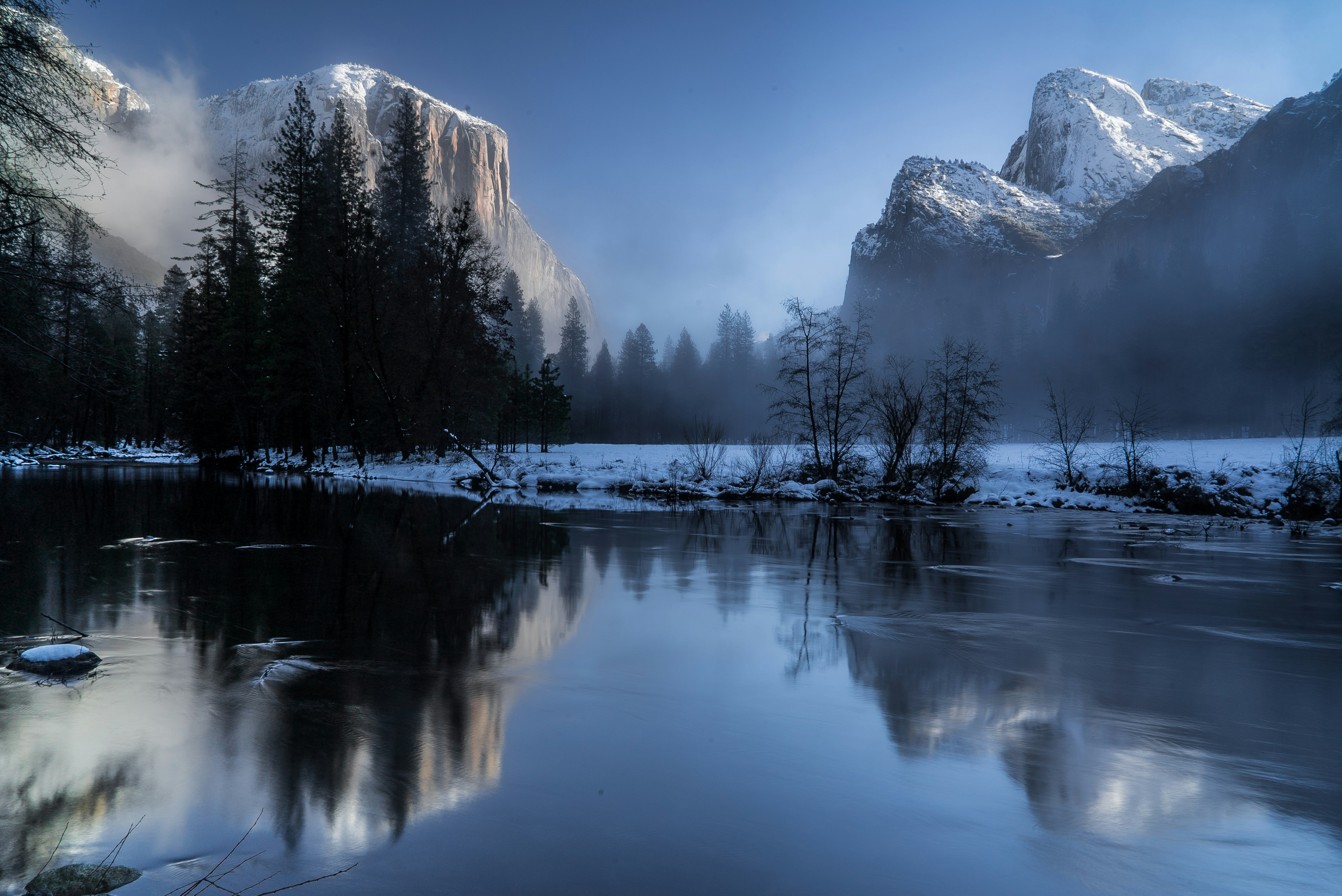 reflection of mountains and trees on body of during snow